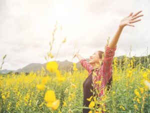 Woman with arms outstretched in a field of yellow flowers