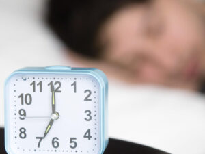 Alarm clock on table in front of sleeping man