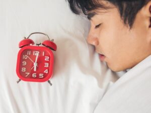 Man sleeping with alarm clock beside