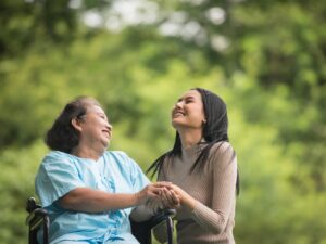 Elderly woman on wheelchair happily smiling with daughter