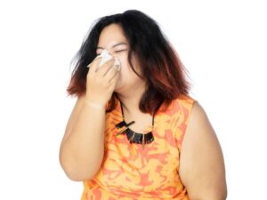 Woman with nasal congestion covering nose with a tissue